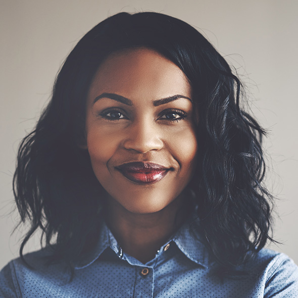 Betterdays Healthcare Confident woman with a gentle smile, sporting wavy hair and wearing a polka dot shirt.